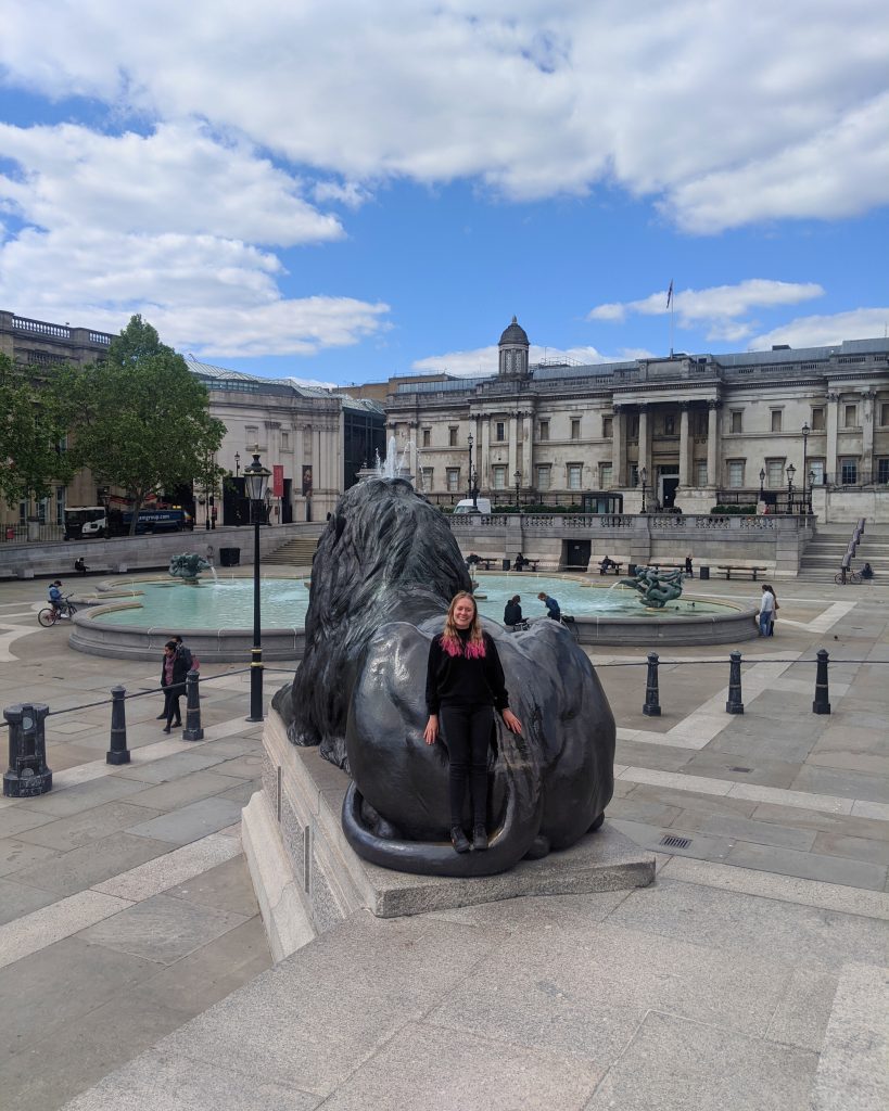 Picture of Jenny, owner of London Localite resting against a lion in Trafalgar Square